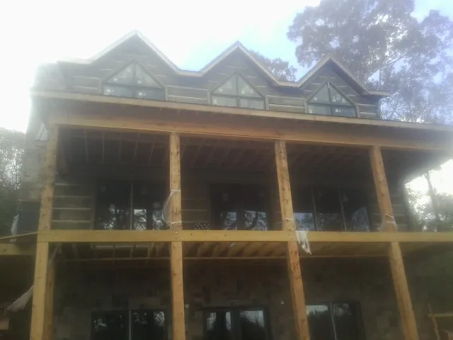 Dormers and porch framing on a large log home under construction — Roof Coating work by our crew in Amboy