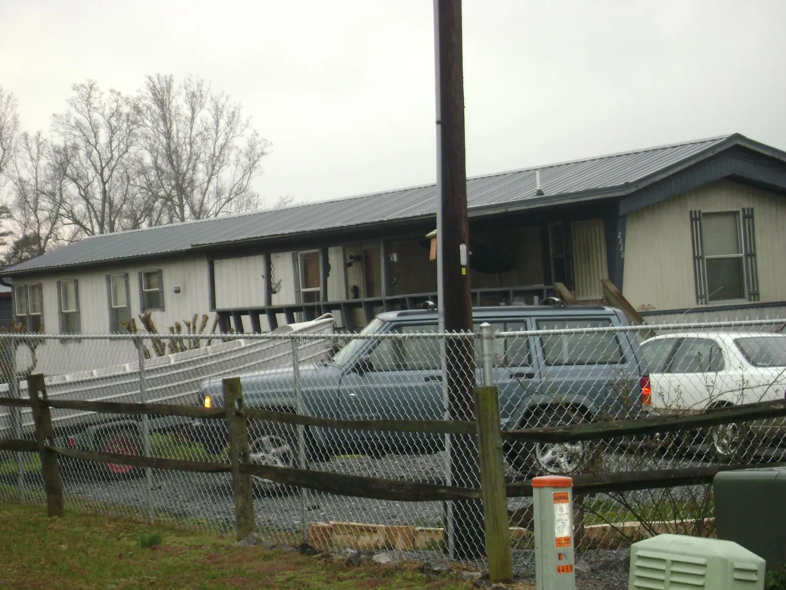 Dark metal roof on a long single story building behind a chain link fence in Amboy
