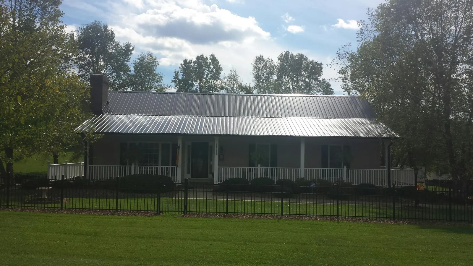 Gray metal roof on a brick ranch with a full width front porch — Gutter Guard Installation work by our crew in Amboy