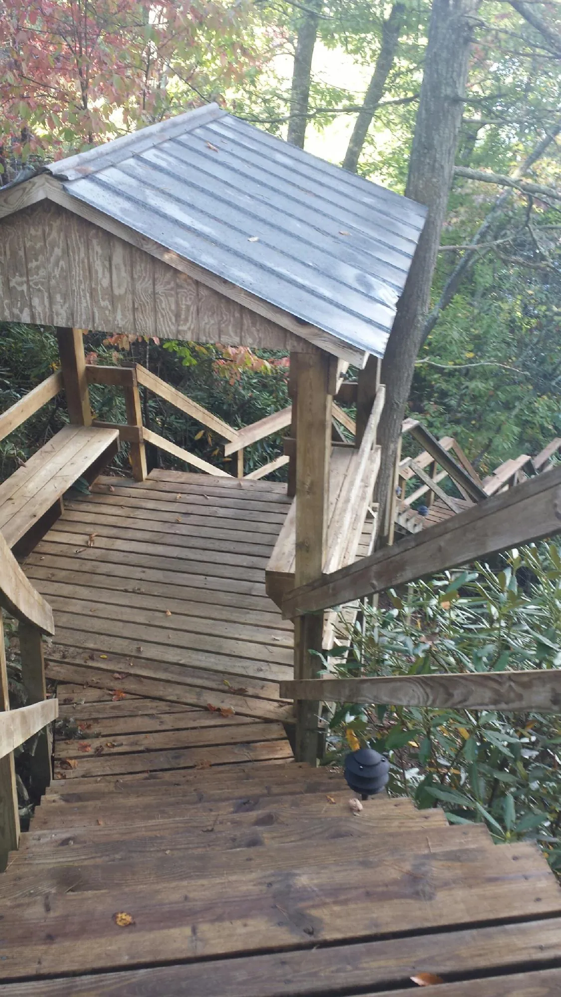 Metal roofed shelter over wooden steps on a wooded walkway — Skylight Repair & Installation work by our crew in Amboy